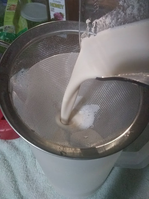 Home-made cashew milk being poured through a strainer