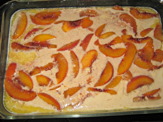 Peach cobbler mixture and batter in a baking dish