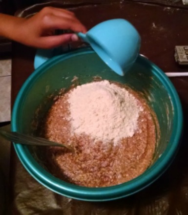 Soy flour being poured into chocolate chip cookie batter