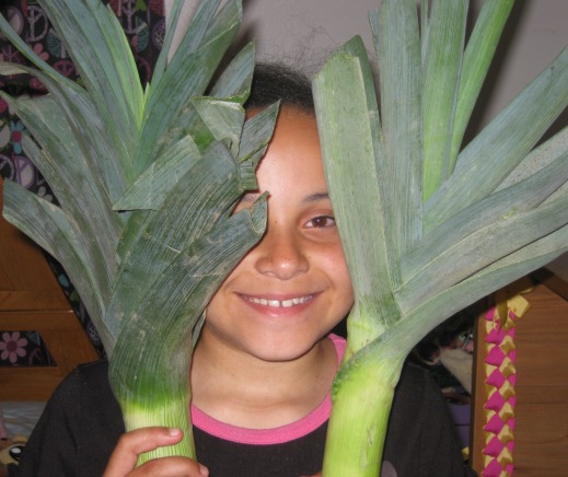 Child holding two giant leeks