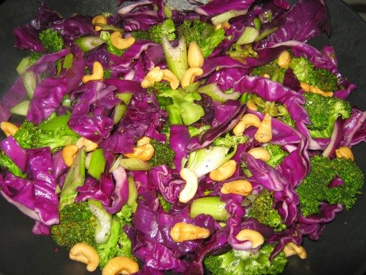 Wok filled with purple cabbage broccoli and cashews